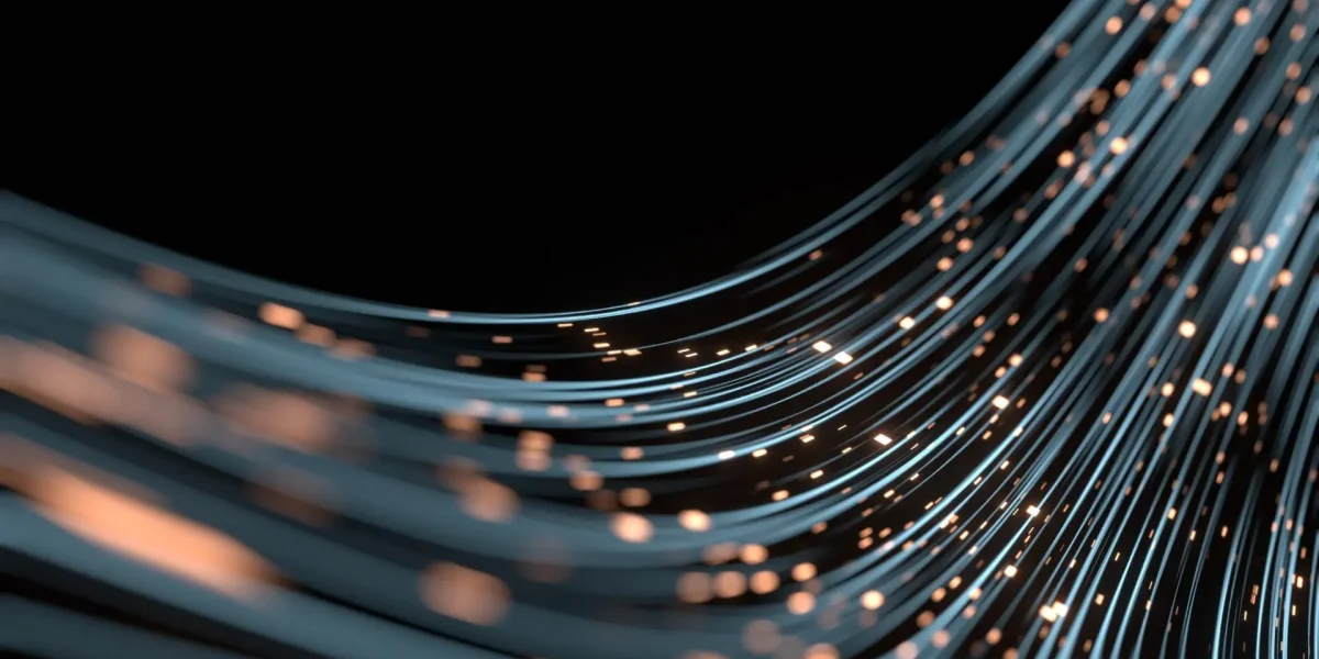 Des câbles de fibre optique bleus courbés, avec des points lumineux orange, circulent en diagonale sur un fond noir, créant une impression de mouvement et de technologie futuriste.
