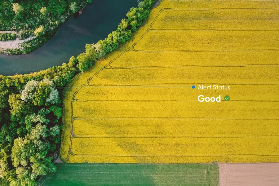 Vue aérienne d'une rivière bordée d'arbres et de terres agricoles jaunes. Le texte superposé sur le champ jaune indique 