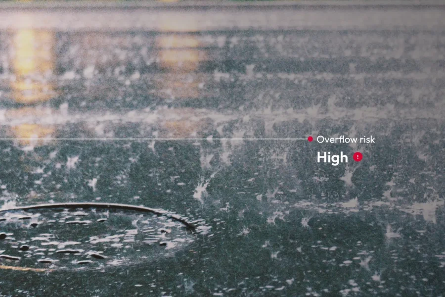 De fortes pluies s'abattent sur une rue de la ville, l'eau s'accumulant autour d'une bouche d'égout. Le texte de droite indique 