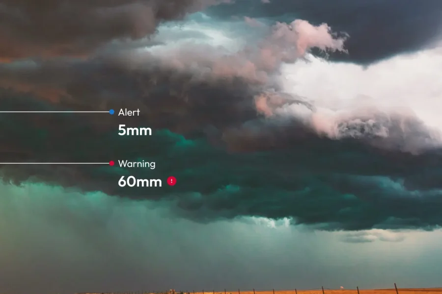 De sombres nuages d'orage se profilent au-dessus de terres agricoles ouvertes. Le texte indique les niveaux de précipitations : 