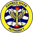 Le logo de la Zambezi River Authority présente une bordure circulaire jaune avec les mots Zambezi River Authority et un emblème central représentant des flèches et des flammes sur des lignes ondulées bleues et blanches.