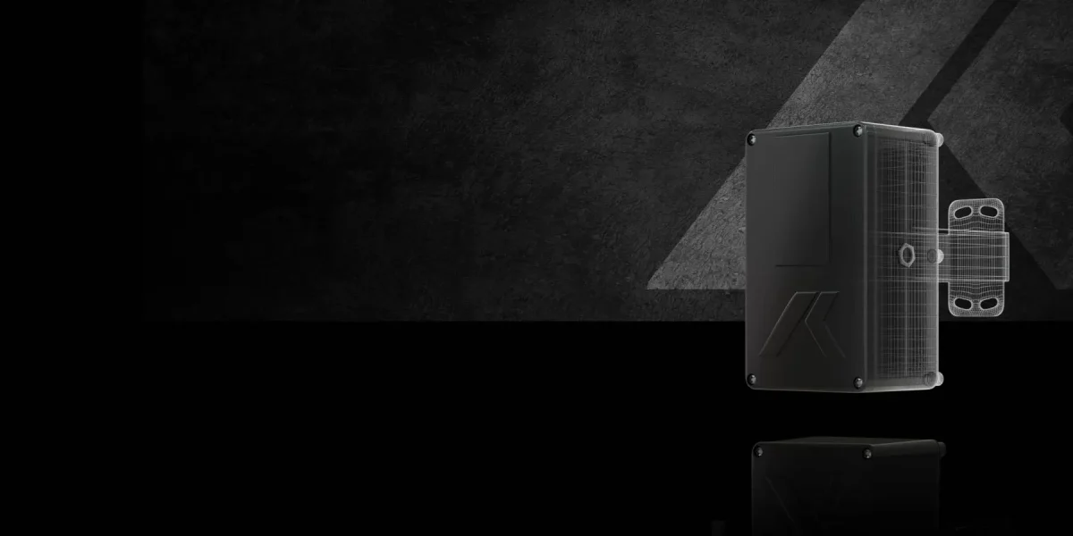 Un appareil électronique rectangulaire, noir et élégant, avec des boulons aux coins, placé à la verticale sur un fond sombre et texturé avec un accent lumineux triangulaire. L'appareil porte un logo géométrique subtil sur sa face avant.