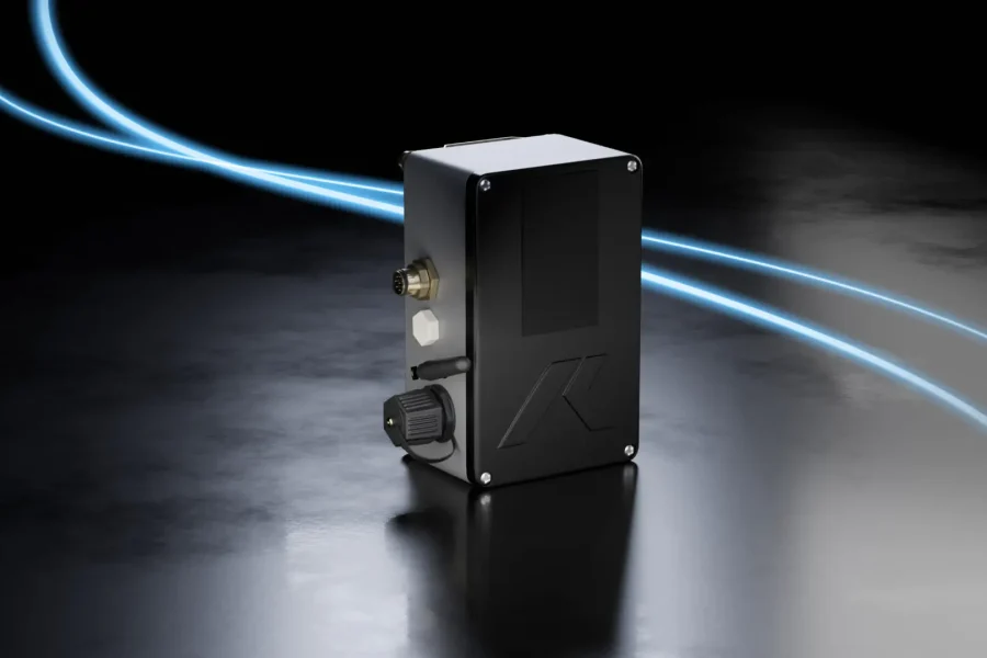 Un appareil électronique rectangulaire noir avec des ports et des connecteurs est posé sur une surface réfléchissante, avec deux lignes bleues lumineuses qui s'incurvent dans l'arrière-plan sombre.